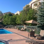 Pool furniture and a sun brella arranged around the pool