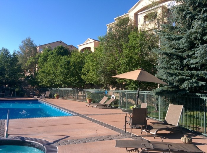 Pool furniture and a sun brella arranged around the pool